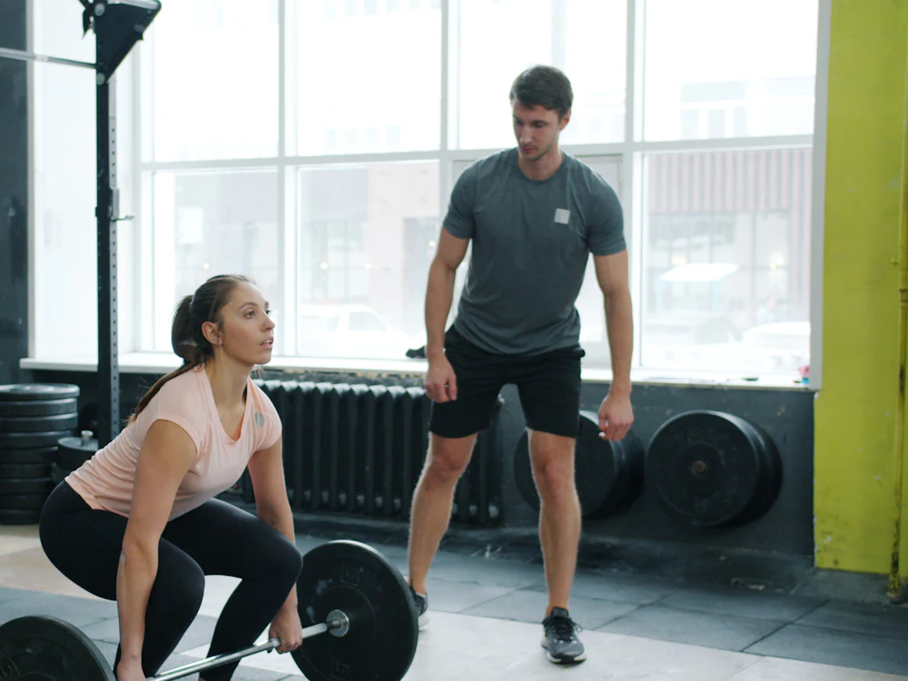 A coach watching an athlete lift
