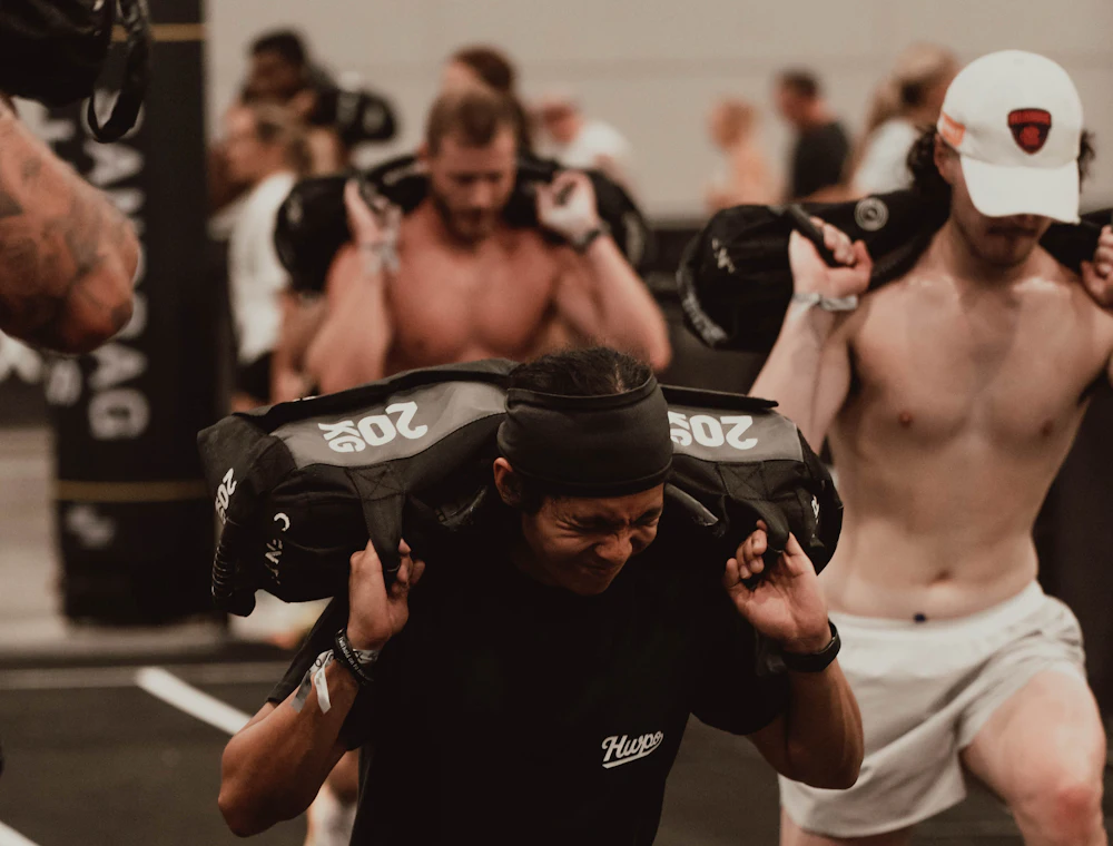 Athletes carrying sandbags during a conditioning session