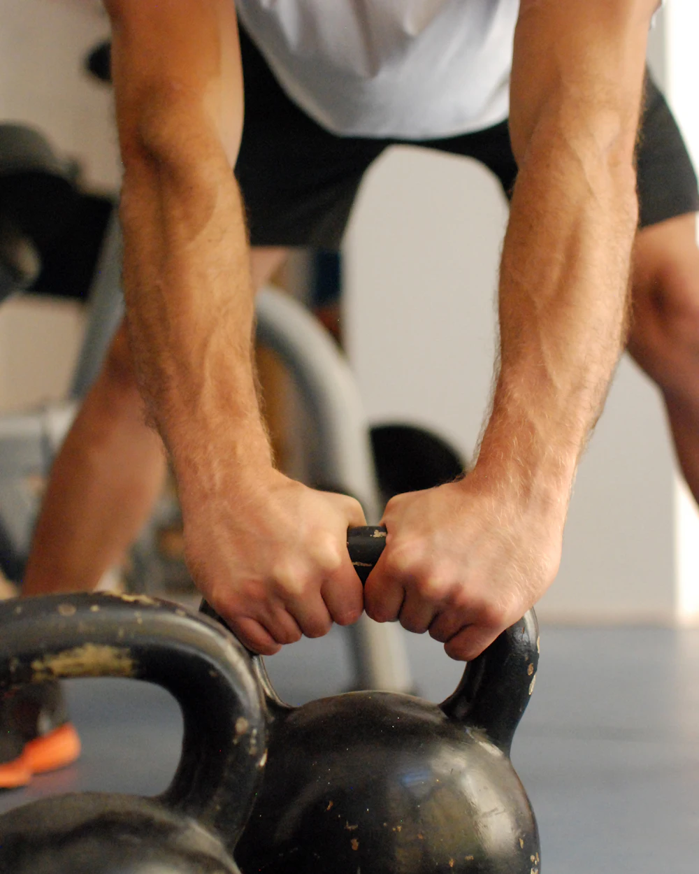 Gripping a pair of kettlebells
